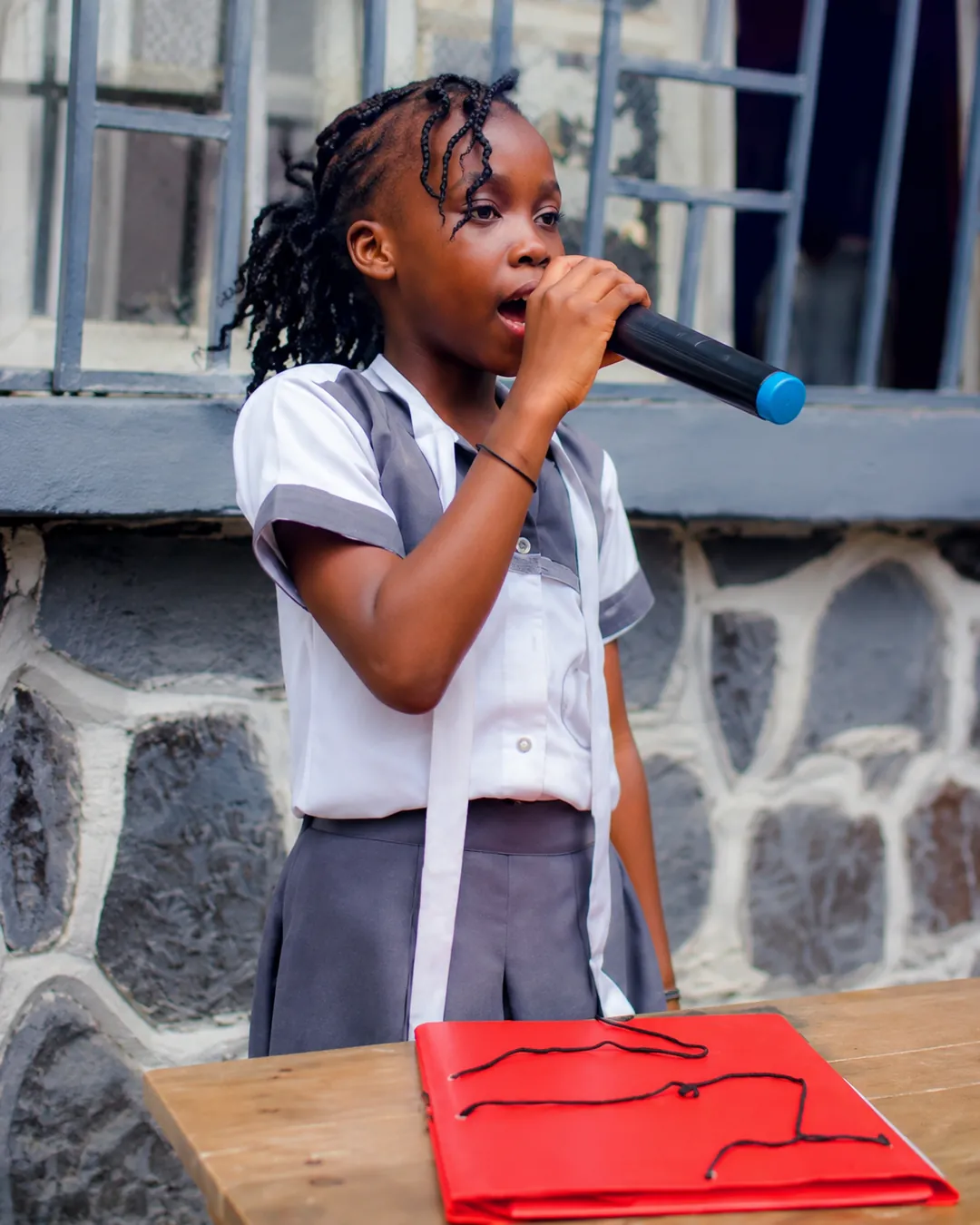 Une élève récite au micro devant l'école
